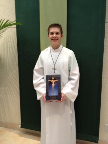 Baumann wears a white alb signifying his status as an altar server, a youth who helps the priest with the mass.