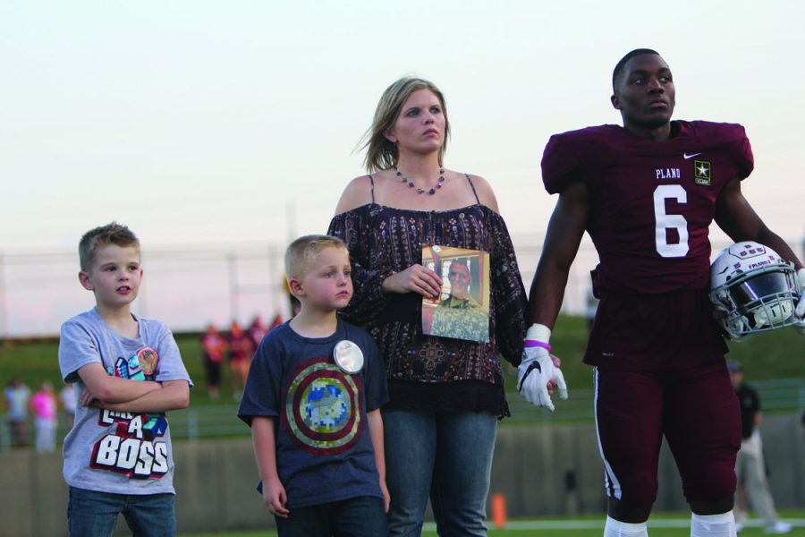 Junior Seagol Mbua stands with the family of First Lieutenant Robert Welch III during Plano’s Maroon Out game against MacArthur. (Photo by Jordyn Carter)