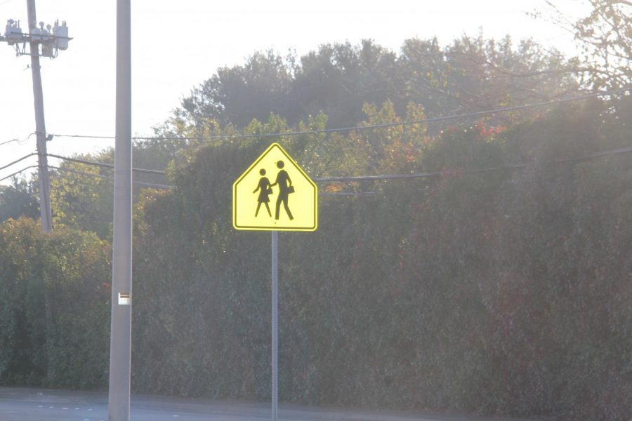 A yield to pedestrians sign next to a busy street gone ignored or unnoticed by many drivers.