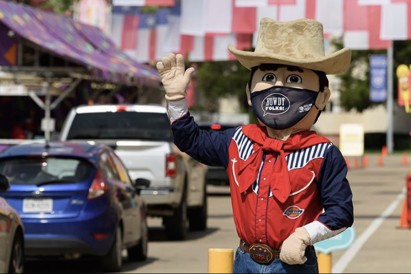 Big Tex waves to fair participants in their cars.